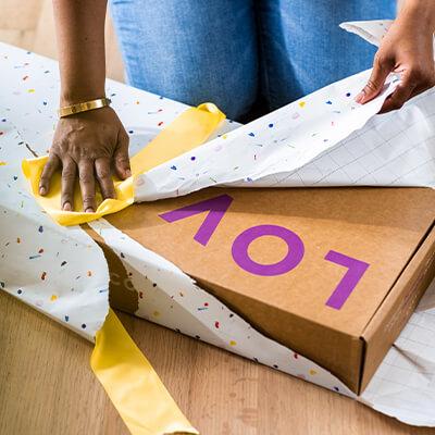 a parent unwrapping a colorfully wrapped Lovevery Play Kit